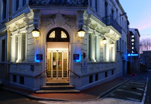 a white building with a door and stairs on a street at Hôtel La Résidence in Narbonne