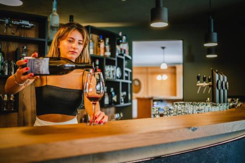 a woman pouring a glass of wine at a bar at Dolomitenhotel Weisslahnbad in Tires