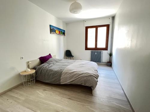 a white bedroom with a bed and a window at Superbe appartement centre ville in Nîmes