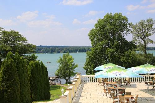 a patio with tables and umbrellas next to a lake at Hotel Resort Märkisches Meer in Diensdorf-Radlow