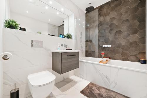 a bathroom with a toilet and a tub and a sink at Livestay-Luxury London Penthouse with Enviable Views in London