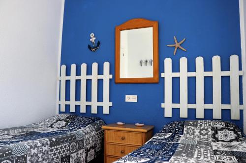 una camera blu con due letti e uno specchio di CHALET CON PISCINA PRIVADA a Torrevieja