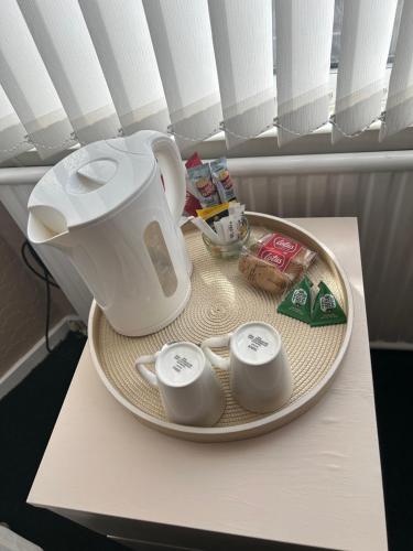 a plate with a tea pot and three cups on a table at Village Rooms in Marton