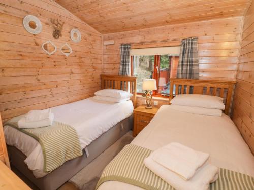 two beds in a room with wooden walls at 6 Astbury Falls in Bridgnorth