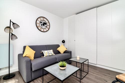 un salon avec un canapé et une horloge au mur dans l'établissement Les Tambourins By SCLS Locations, à Cannes