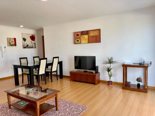 a living room with a table and chairs and a tv at Ocean Terrace House in Ribeira Grande