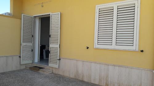 two shuttered windows on the side of a building at Casa sole e luna in Porto Cesareo