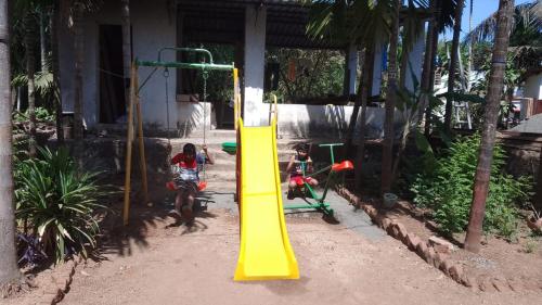 a playground with a yellow slide in front of a building at Tendulkar Beach Resort in Diveagar