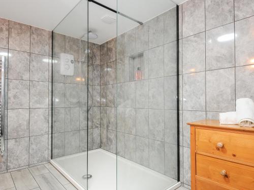 La salle de bains est pourvue d'une douche avec une porte en verre. dans l'établissement Owl Barn, à Liskeard
