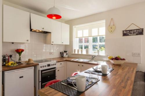 een keuken met witte kasten en een houten aanrecht bij The Willow Studio - peaceful retreat near Whitstable seaside in Kent
