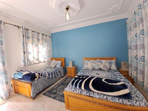2 camas en un dormitorio con paredes azules en Diafa, en Tánger