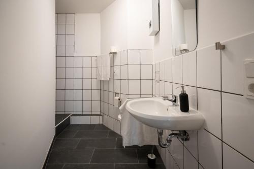 een witte badkamer met een wastafel en een spiegel bij Old Town Apartment 2 rooms/baths in Düsseldorf