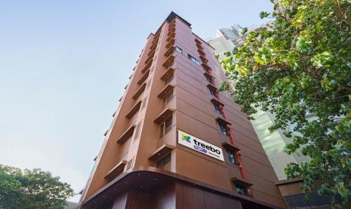 Treebo Tryst Savera Inn في مومباي: مبنى بني طويل مع علامة عليه