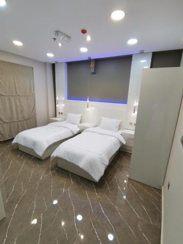 two beds in a room with white sheets at Marina H in Sohar