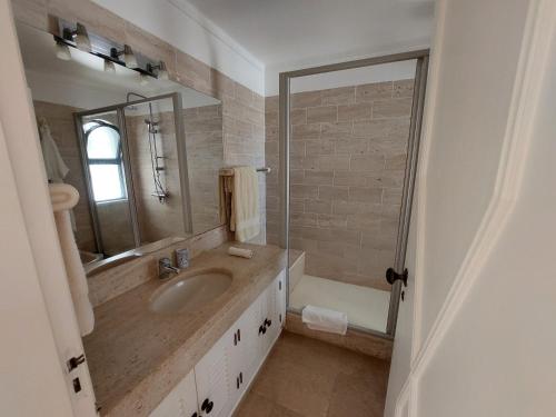 ein Badezimmer mit einem Waschbecken, einem Spiegel und einer Badewanne in der Unterkunft Ancão Beach Apartment in Almancil