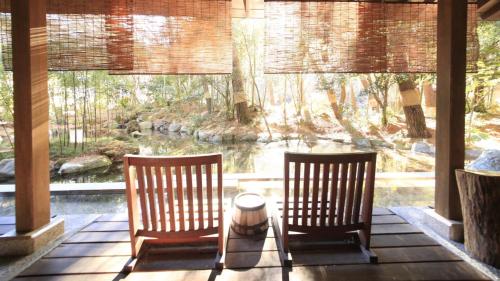 two chairs sitting on a porch looking out at the water at Shimobe Hotel in Minobu