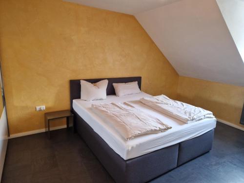 uma cama com lençóis brancos e almofadas num quarto em Wohnen auf Zeit City Speyer em Speyer