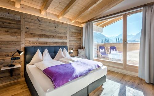 a bedroom with a bed and a large window at Almdorf Almlust in Flachau