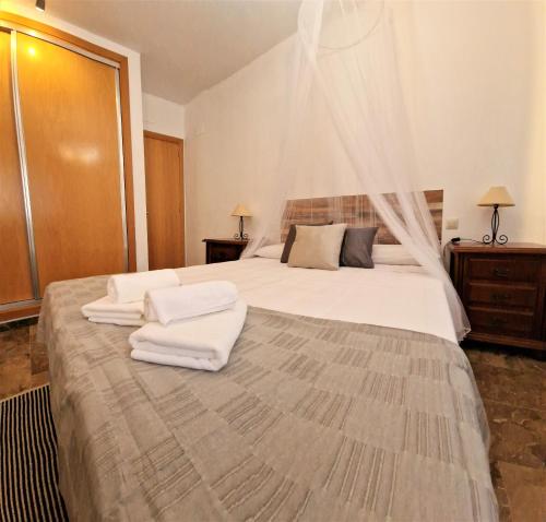 1 dormitorio con 1 cama grande y toallas. en DS Dúplex Acera del Río, parking opcional, en Córdoba