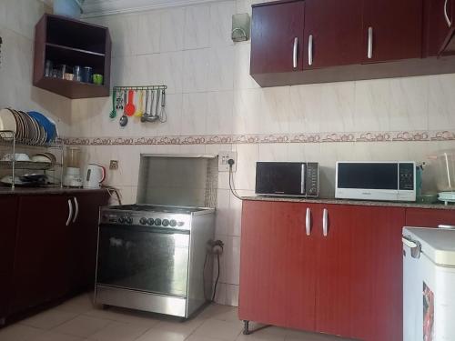 a kitchen with a stove and a microwave at Arsenal's Lodge in Abuja