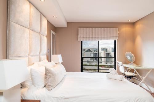 Un dormitorio con una gran cama blanca con ventana. en Modern Beachfront Eden on the Bay 210- 2 bedroom, 2 bathroom, en Bloubergstrand