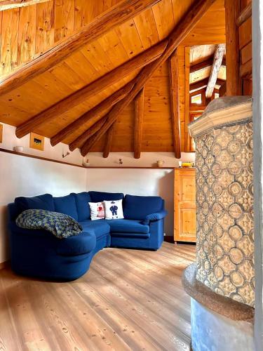 ein blaues Sofa im Wohnzimmer mit Holzdecken in der Unterkunft Casa Gianmoena in Cavalese
