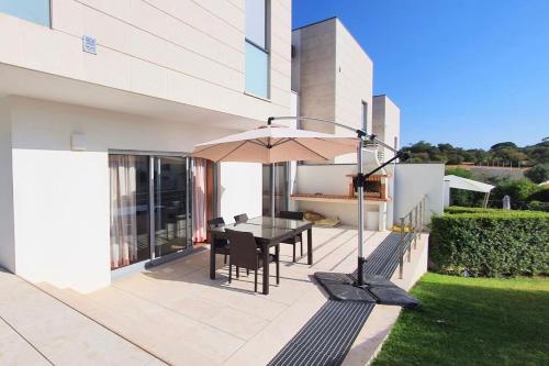 un patio con mesa y sombrilla en Modern 3Bedroom Duplex W/Pool by LovelyStay en Alcantarilha