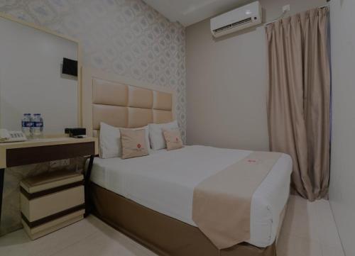 a bedroom with a large white bed and a desk at Osaka Hotel Batam in Nagoya