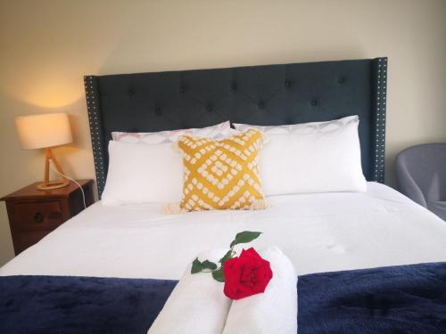 uma cama com lençóis brancos e uma rosa vermelha em Rose Room em Auckland