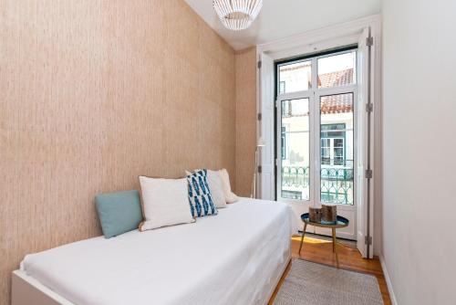 een slaapkamer met een wit bed en een raam bij Chic Urban Apartment at Downtown with a Sunny Balcony! in Lissabon