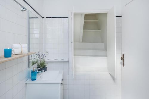 een witte badkamer met een douche en een wastafel bij Chic Urban Apartment at Downtown with a Sunny Balcony! in Lissabon