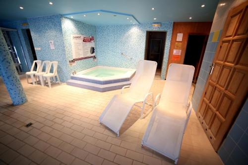 een badkamer met een bad met witte stoelen en een tafel bij Hotel Diament in Grzybowo