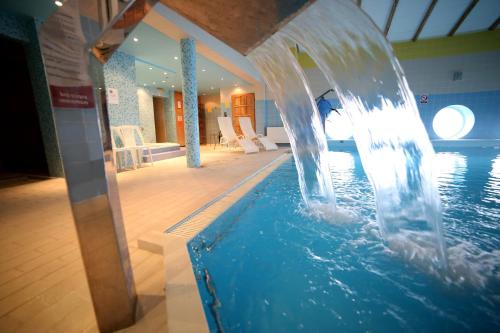 a water fountain in a swimming pool in a building at Hotel Diament in Grzybowo