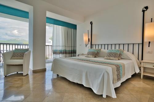 a bedroom with a large bed and a balcony at El Faro Hotel & Spa in Porto Conte
