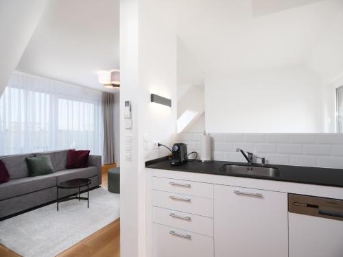 a white kitchen with a sink and a living room at MyFavorit by Duschel Apartments Vienna in Vienna
