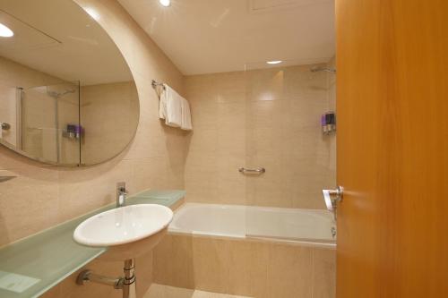 a bathroom with a sink and a tub and a mirror at Sercotel Hotel Zurbarán in Palma de Mallorca