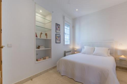 a white bedroom with a white bed and a window at Atico con Terraza de vistas inmejorables in Madrid