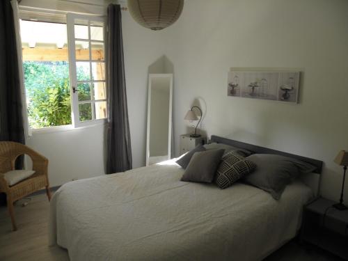 - une chambre avec un lit blanc avec des oreillers et une fenêtre dans l'établissement Gîte en Ardèche Méridionale - Les Berbéris, à Chandolas