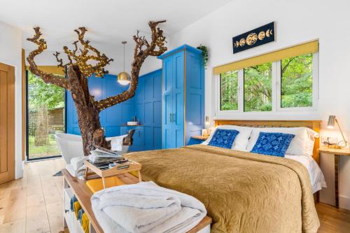 a blue bedroom with a bed and a tree in it at Ivy Cottage Holiday Cabins in Southampton