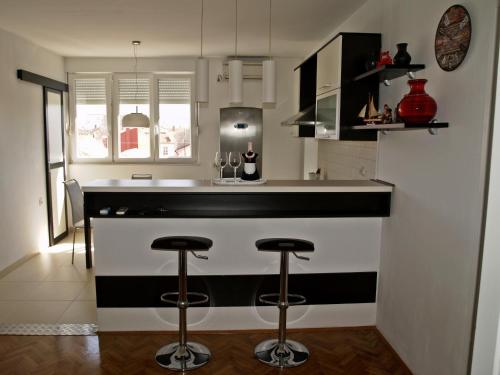 una cocina con encimera y taburetes en blanco y negro en Apartment Roxy, en Zadar