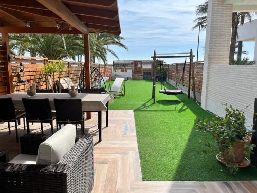 un patio con césped verde, mesa y sillas en Casa en primera linea de playa, en Puzol