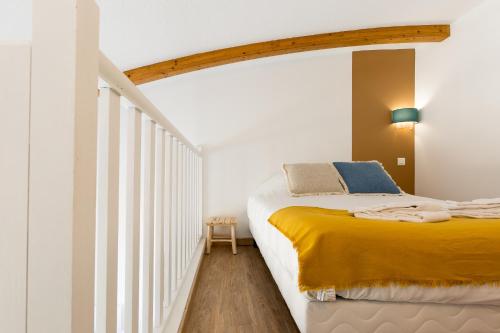 a bedroom with a bed with a yellow blanket at Appart'Hôtel Les Lofts du Grand Lac de Lozère in Langogne