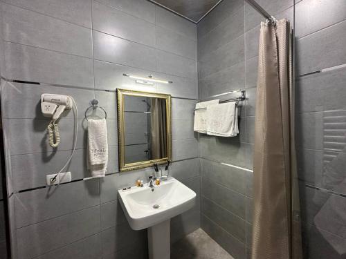 ein Bad mit einem Waschbecken, einem Spiegel und einer Dusche in der Unterkunft Ideal Hotel in Samarkand