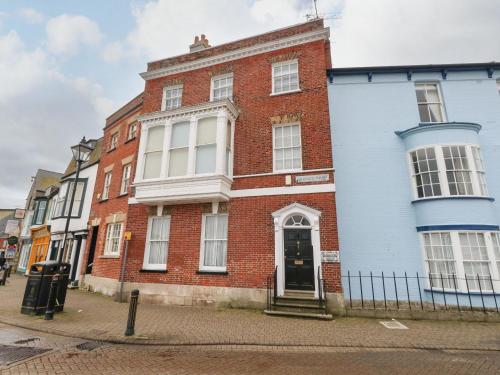 a red brick building with a black door on a street at Monarch in Weymouth