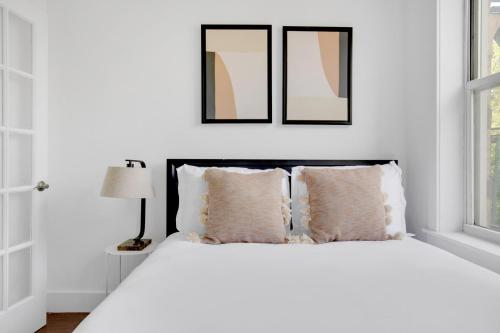 a white bedroom with a white bed with two pillows at Sunlit LES 1BR w WD nr BD train NYC-865 in New York