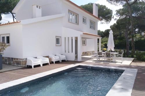 a villa with a swimming pool in front of a house at Banzão home PineForest family &friends pool garden in Colares
