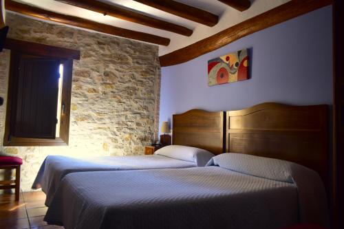 a bedroom with two beds and a stone wall at La Posada in Cantavieja