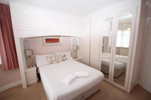 a white bedroom with a bed and a mirror at The Ruislip Bungalow in Ruislip