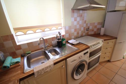 a kitchen with a sink and a washing machine at The Ruislip Bungalow in Ruislip