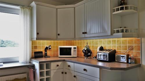 a kitchen with white cabinets and a counter with a microwave at The Bridge in Kippford